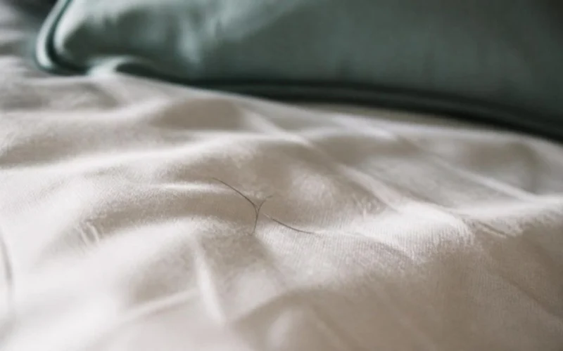 Cabellos sueltos sobre una funda de almohada de lino blanco con luz de mañana